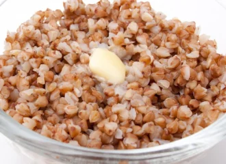 A bowl of cooked buckwheat groats (kasha) topped with a pat of melting butter